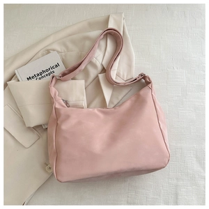 Close-up of a light pink crossbody hobo bag with a wide adjustable shoulder strap