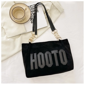 Detail of black suede tote bag with golden chain strap and HOOTO letter embroidery
