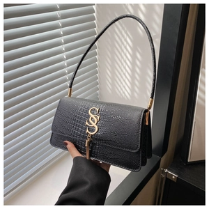 Detail of black crocodile embossed leather shoulder bag with gold SS logo and tassel