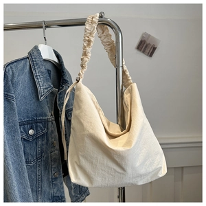 Detail of a large off-white nylon cloud tote bag with a pleated scrunchie shoulder strap