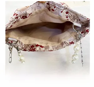 Close-up of jacquard fabric bag showing interior lining and white pearl strap detail