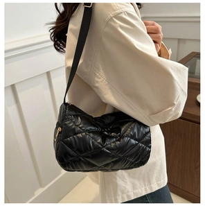Détail d'un sac à bandoulière en nylon matelassé noir avec une fermeture éclair dorée