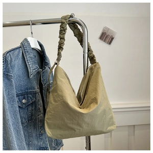 Detail of green ruched cloud strap and water-resistant nylon texture on tote bag
