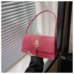 Detail of pink faux crocodile leather handbag with gold S-logo and chain fringe