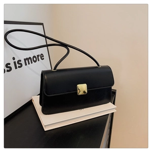Dettaglio di una borsa a tracolla nera minimalista con chiusura quadrata in metallo dorato