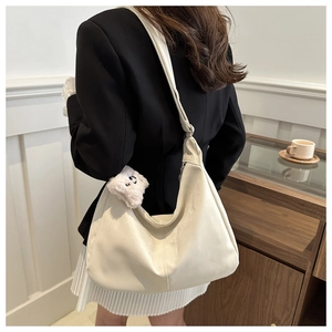 Detail view of cream PU leather crescent bag with cute plush bear charm on model