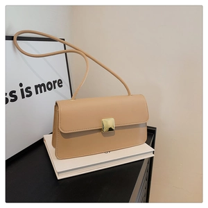 Dettaglio della fibbia quadrata in metallo dorato su borsa a tracolla beige minimalista