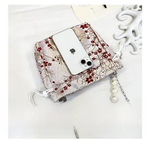 Detail of floral jacquard bag with pearl chain strap and smartphone size comparison