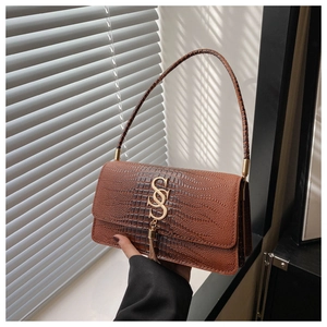 Detail of brown crocodile pattern shoulder bag with gold SSS logo and tassel accent