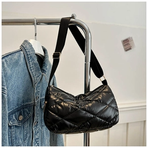 Détail du sac matelassé noir en nylon brillant avec fermeture éclair en métal doré