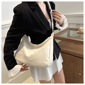 Detail view of the cream crescent hobo bag made of matte suede material worn on shoulder