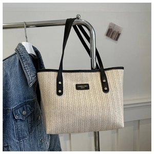 Détail du sac cabas beige tissé avec logo en cuir noir et bandoulière assortie