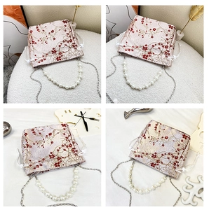 Detail of floral embroidered satin tote with pearl handle and metal chain strap