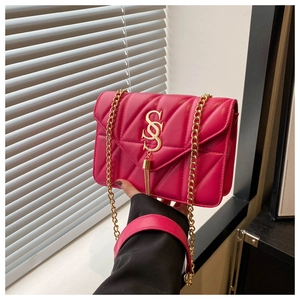 Detail of hot pink quilted shoulder bag with gold chain and metal tassel ornament