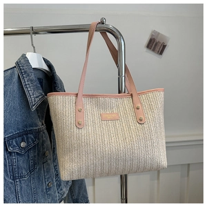 Détail du sac cabas en paille avec anses en cuir rose et rivets dorés de renforcement