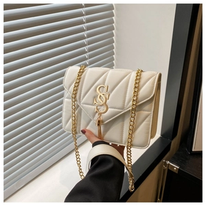 Detail of white quilted handbag featuring golden SS logo, tassel, and chain strap