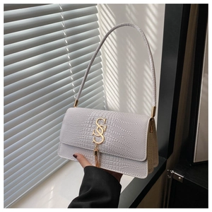 Close-up of white crocodile texture shoulder bag with gold metal logo and fringe detail