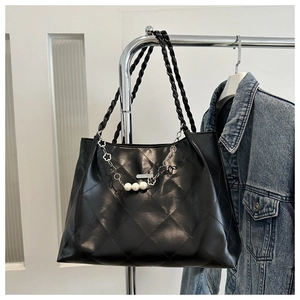 Detail of black quilted tote bag with pearl and floral chain decoration