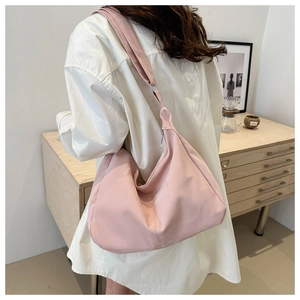 Pink nylon hobo bag styled with a white shirt in a cozy indoor setting
