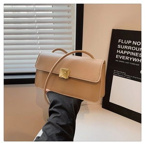 Dettaglio di una borsa a tracolla beige minimalista con fibbia dorata e pelle liscia