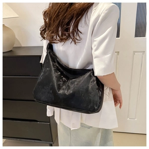 Detail of vintage textured black leather crossbody bag worn as a shoulder bag