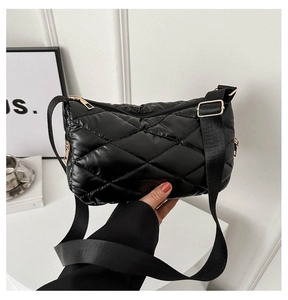 Détail du sac bandoulière matelassé noir brillant avec fermeture éclair dorée et sangle large