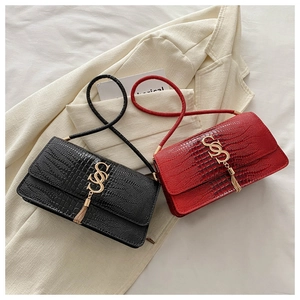 Close-up of black and red crocodile pattern leather handbags with gold tassel buckles