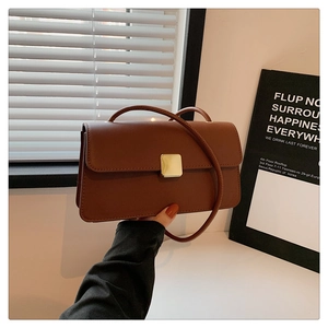 Dettaglio borsa in pelle color caramello con fibbia quadrata dorata e tracolla sottile