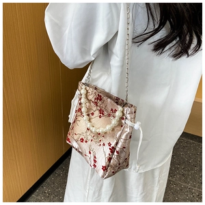 Detail of champagne satin crossbody bag with red plum embroidery and pearl handle
