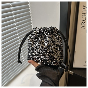 Detailed view of silver sequin bucket bag featuring a soft black drawstring closure