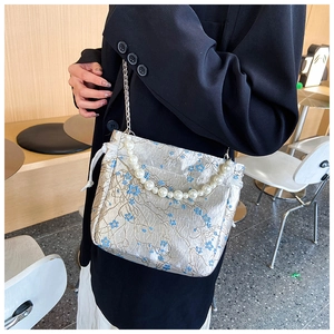 Detail of silver floral jacquard fabric and elegant pearl handle on a small tote bag