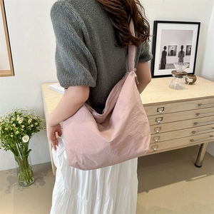 Pink crescent nylon hobo bag with pleated texture and wide strap shown on a model