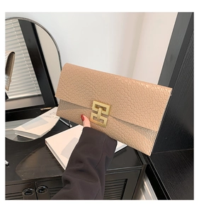Détail de la texture serpent beige et du fermoir géométrique doré sur la pochette enveloppe