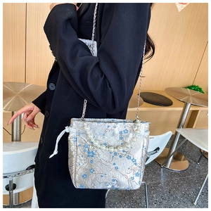 Detailed shot of silver jacquard drawstring bag with floral embroidery and pearl handle