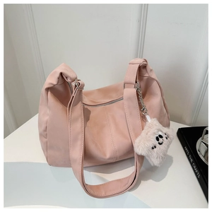 Detail view of pink hobo bag featuring soft texture and plush charm accessory
