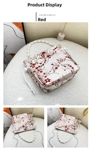 Detail of red floral embroidery on cream satin bucket bag with elegant pearl handle