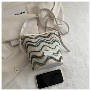 Detail of embroidered wavy pattern bucket bag with leather strap and fashion label