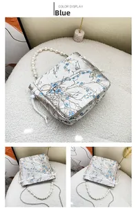 Detail view of jacquard fabric texture and large pearl handle on blue floral handbag
