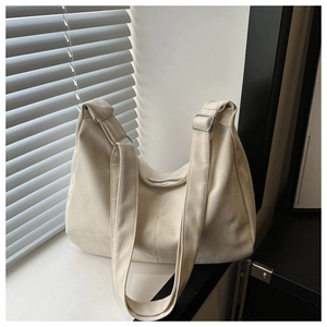 Detail of cream suede hobo bag with adjustable silver buckle and soft light shadows