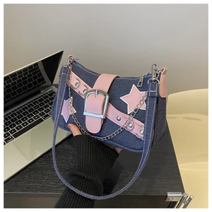 Detail of blue denim shoulder bag featuring pink star patch and silver metal buckle