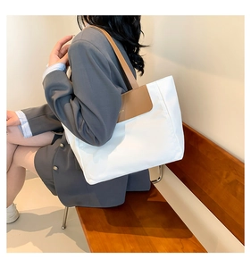 Detail of cream canvas tote bag with brown leather shoulder straps and flap closure
