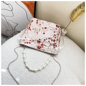 Close-up of pink jacquard bucket bag with floral embroidery and pearl handle strap