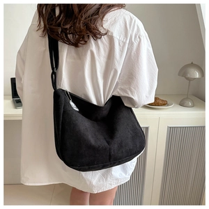 Detail of black corduroy crossbody bag with vertical texture and white cartoon charm