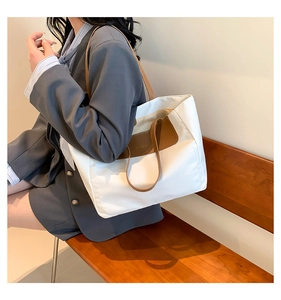 Close-up of cream canvas tote bag with brown leather accents and FASHION embossed detail