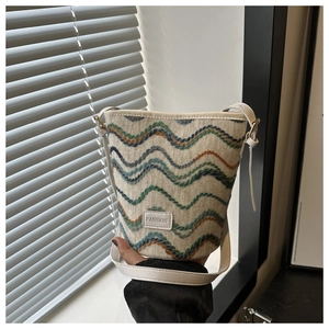 Detail of knit bucket bag featuring wavy patterns and a centered FASHION brand label