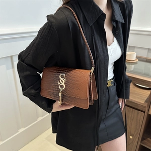 Brown crocodile texture PU leather shoulder bag with gold logo and tassel on model