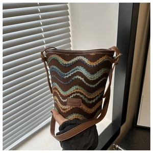 Detail of the wave pattern embroidery and leather fashion label on the shoulder bucket bag