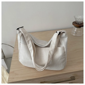 Detailed view of beige corduroy hobo bag texture with front pocket and zip closure