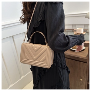 Dettaglio borsa a tracolla beige trapuntata chevron con manico superiore e cinturino