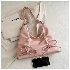 Dettaglio della borsa rosa con fiocchi decorativi e logo argento su superficie in pelle